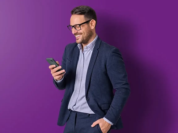 Geschäftmann lächend und auf sein Smartphone schauend